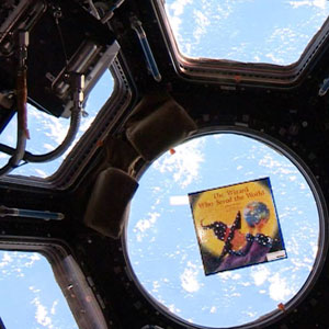 The Wizard Who Saved the World floating in the International Space Station, with Earth visible through the window behind it, as part of the Story Time From Space program. 
